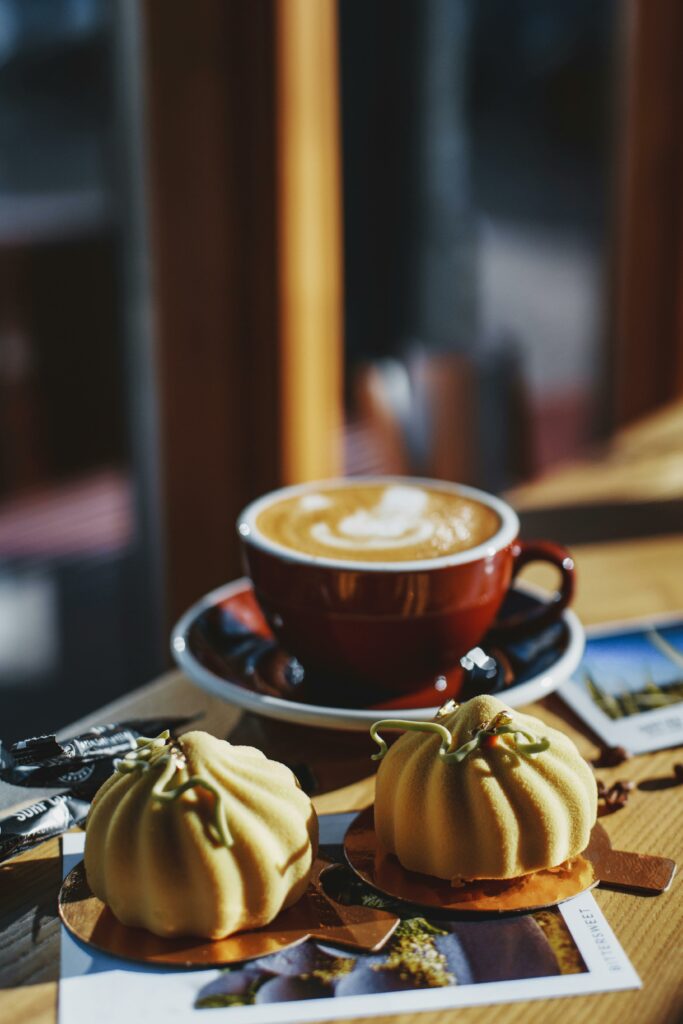 Elegant setup of a cappuccino with pastries in a cozy sunlit café atmosphere.